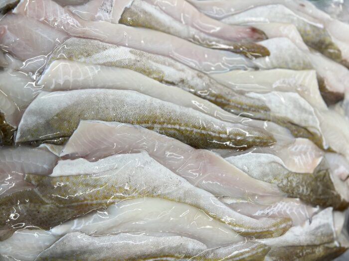 Fresh, raw cod fillets stacked neatly.